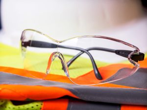 A pair of impact-resistant safety glasses sitting atop a bright orange safety vest.